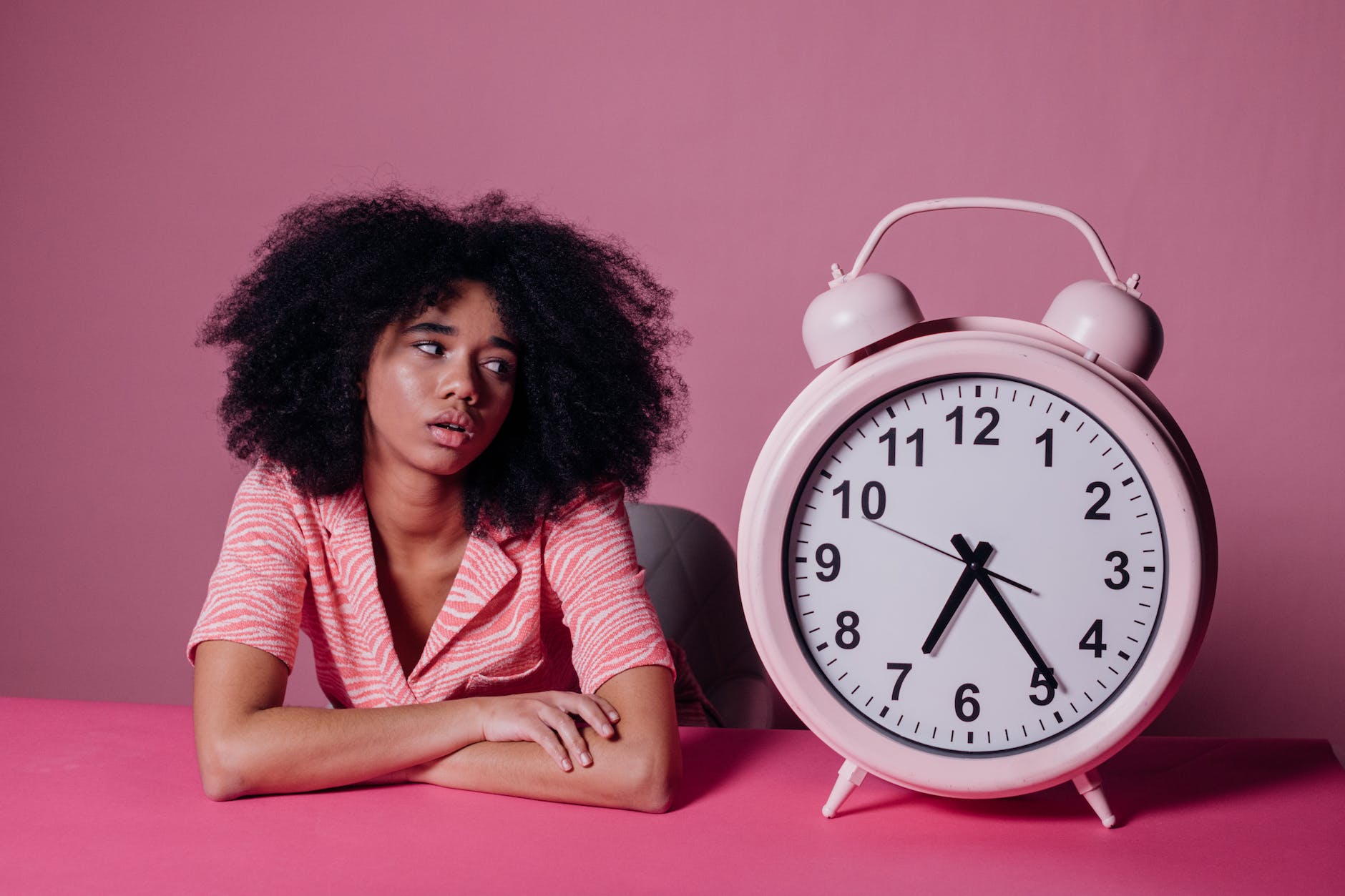 woman looking at a big pink alarm clock